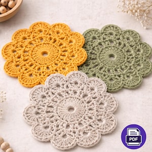 Może przedstawiać: Trzy ręcznie robione podkładki pod kubki z szydełka w odcieniach żółci, zieleni i beżu. Każda podkładka ma kwiatowy wzór z centralnym otworem i falistymi krawędziami. Podkładki są prezentowane na jasnej powierzchni.