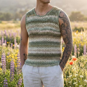 May include: A sleeveless, crochet top in shades of green, beige, and white. The top has a striped pattern and a rounded neckline. The person is standing in a field of wildflowers, wearing light-colored shorts.