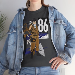 Può includere: Una t-shirt grigio scuro con la grafica di un personaggio anime in uniforme color marrone chiaro, uno scheletro bianco e il numero 86 con la scritta EIGHTY SIX. La t-shirt è indossata sotto una giacca di jeans azzurra con bottoni metallici.