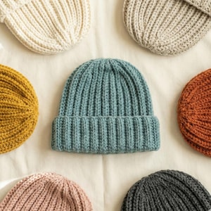 May include: A set of three ceramic mugs with a speckled, matte finish. The mugs are in cream, light grey, and dark grey. Each mug has a simple, minimalist design and a rounded handle.