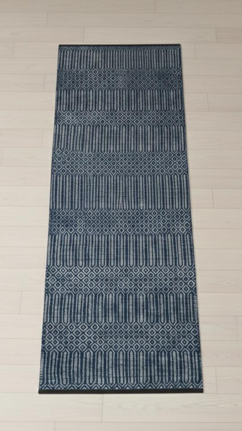 Puede incluir: Una alfombra rectangular tipo pasillero con un patr&oacute;n geom&eacute;trico en azul marino oscuro y gris claro. El dise&ntilde;o consiste en bandas horizontales alternas de formas de diamante repetidas y columnas hexagonales verticales alargadas.