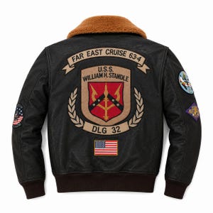 Peut inclure: Un blouson aviateur en cuir noir avec un col en fausse fourrure marron et des poignets c&ocirc;tel&eacute;s. Le dos pr&eacute;sente un grand &eacute;cusson brod&eacute; U.S.S. WILLIAM H. STANDLE DLG 32, une banni&egrave;re FAR EAST CRUISE 63-4, un drapeau am&eacute;ricain et des &eacute;cussons sur les manches.