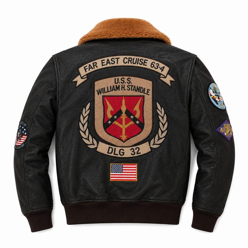 Peut inclure: Un blouson aviateur en cuir noir avec un col en fausse fourrure marron et des poignets c&ocirc;tel&eacute;s. Le dos pr&eacute;sente un grand &eacute;cusson brod&eacute; U.S.S. WILLIAM H. STANDLE DLG 32, une banni&egrave;re FAR EAST CRUISE 63-4, un drapeau am&eacute;ricain et des &eacute;cussons sur les manches.
