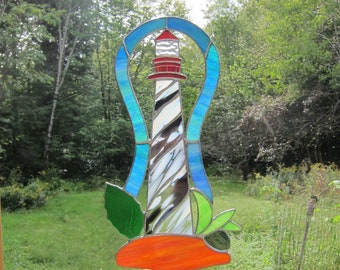 Stained glass Fantasy Island Lighthouse, suncatcher, window hanging. Blue, green and white wispy border glass. 13.5 inches high by 7 wide.