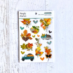 Könnte beinhalten: Ein Stickerbuch mit weißem Hintergrund und bunten Stickern mit Herbstmotiven. Die Sticker zeigen Kürbisse, Blätter, Herzen und die Worte "Herbst ist meine Lieblingszeit" und "Ernte".