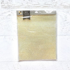 May include: A sheet of gold self-adhesive rhinestones in a clear plastic package. The package has the text "Metallic Rhinestone Self-Adhesive Sheet" on it.