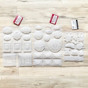 May include: Three clear plastic sheets with various designs for crafting. The sheets contain images of flowers, frames, and other decorative elements. The sheets are labeled "Impression Obsession".