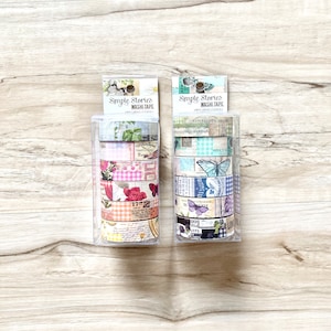 May include: Two packages of Simple Stories Washi Tape. Each package contains five rolls of patterned tape with floral, butterfly, and vintage designs. The tape is in a clear plastic package with a white label.