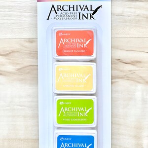 May include: Four ink pads in a clear plastic packaging. The ink pads are labeled "Ranger Archival Ink" and are in the colors bright tangelo, chrome yellow, vivid chartreuse, and manganese blue.