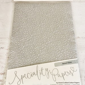 May include: A pack of 5 sheets of A4 size, 150gsm, lignin free, hand crafted cotton paper with a broken glass texture. The paper is white and has a subtle embossed pattern. The pack is labeled "Speciality Papers" and "Broken Glass".