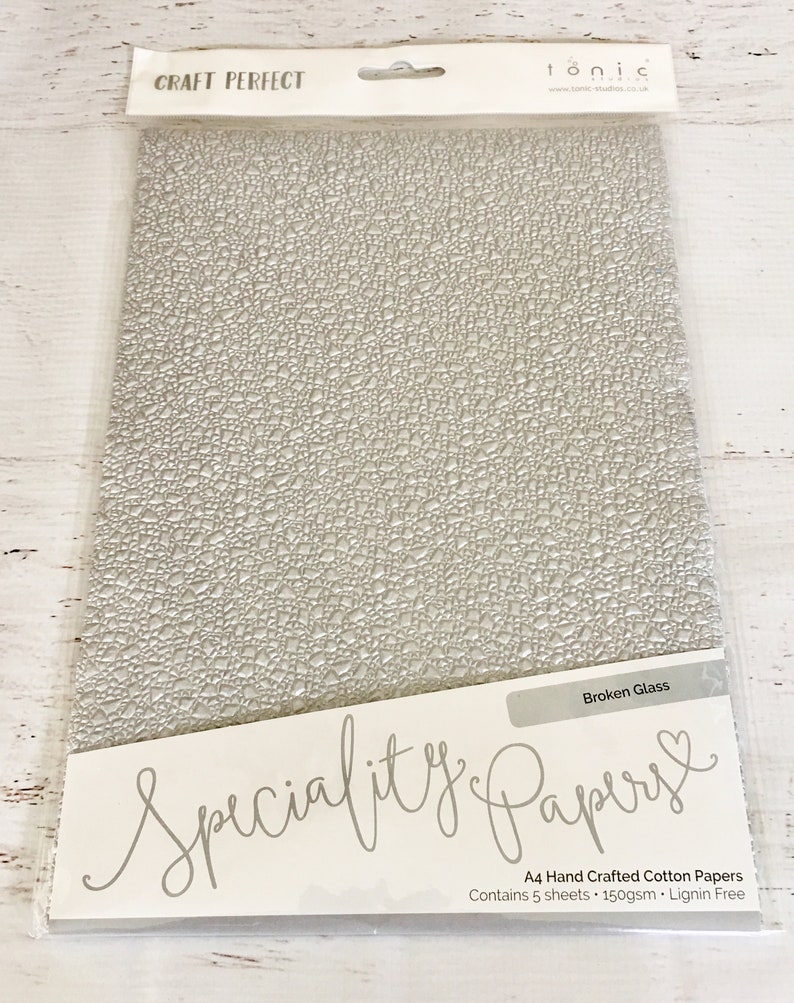 May include: A pack of 5 sheets of A4 size, 150gsm, lignin free, hand crafted cotton paper with a broken glass texture. The paper is white and has a subtle embossed pattern. The pack is labeled "Speciality Papers" and "Broken Glass".
