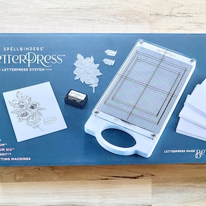Spellbinders Betterpress Letterpress System w/ instructions, Chase & 3 shims, Platen, Press Plates, Black Mini Ink Pad, 15 card panels, tape
