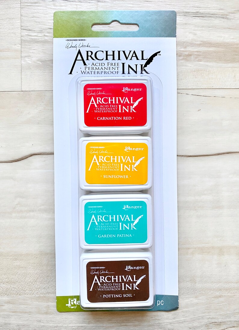 May include: A set of four archival ink pads in a clear plastic packaging. The ink pads are labeled with the colors Carnation Red, Sunflower, Garden Patina, and Potting Soil. The ink pads are acid-free, permanent, and waterproof.