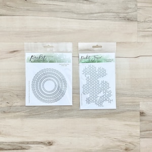 May include: Two packages of metal die cuts for crafting. The package on the left contains four nesting ring dies. The package on the right contains a die cut of a brick wall pattern. Both packages are white with black text and images.