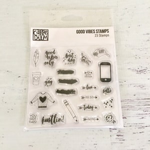 May include: A clear plastic sheet with 23 clear stamps featuring various phrases and designs. The sheet is labeled "Good Vibes Stamps" and "23 Stamps". Some of the stamps include "good vibes only", "best day ever", "lit", "love", "hello", "to do", "today", "note", "you got this", and "kustlin!"