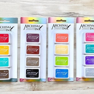 May include: Four sets of four archival ink pads in different colors. Each set includes carnation red, sunflower, turquoise, potting soil, plum, sepia, coffee, jet black, bright apricot, spring green, coral, mango tango, vibrant fuchsia, paradise teal, royal violet, shadow grey, and manganese blue.