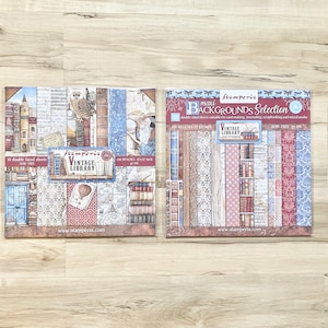 May include: Two packs of double-sided scrapbook paper featuring a vintage library theme. The paper is decorated with images of books, clocks, and other vintage elements. The packs are labelled "Stamperia Vintage Library" and "Stamperia Mini Backgrounds Selection".