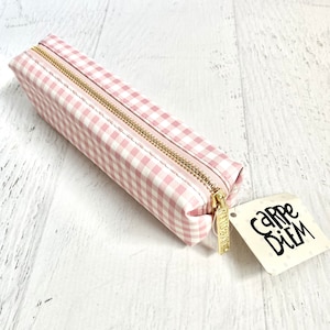 May include: Pink and white gingham pencil case with a gold zipper and a tag that says "Carpe Diem".