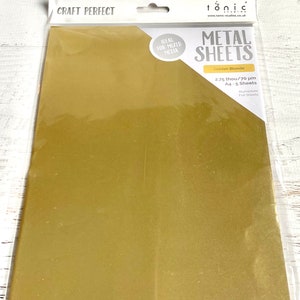 Puede incluir: Un paquete de cinco hojas de papel de aluminio dorado de 2,75 pulgadas de grosor y 70 micras. El paquete est&aacute; etiquetado como "CRAFT PERFECT" y "tonic METAL SHEETS".