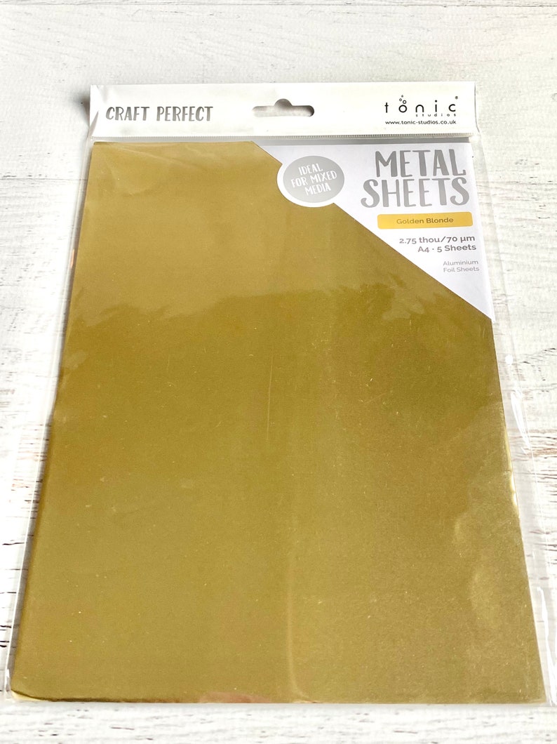 Puede incluir: Un paquete de cinco hojas de papel de aluminio dorado de 2,75 pulgadas de grosor y 70 micras. El paquete est&aacute; etiquetado como "CRAFT PERFECT" y "tonic METAL SHEETS".