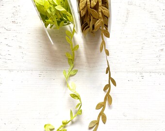 May include: Two spools of green and gold leaf ribbon. The ribbon is made of fabric and has a delicate leaf design. The ribbon is perfect for adding a touch of nature to crafts and decorations.
