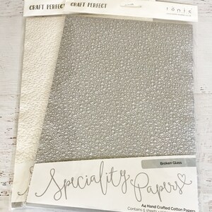 May include: A pack of 5 sheets of A4 size, 150gsm, lignin free, hand crafted cotton paper with a broken glass texture. The paper is a light gray color and is packaged in a clear plastic bag with the brand name "Tonic" and the words "Specialty Papers" printed on the front.