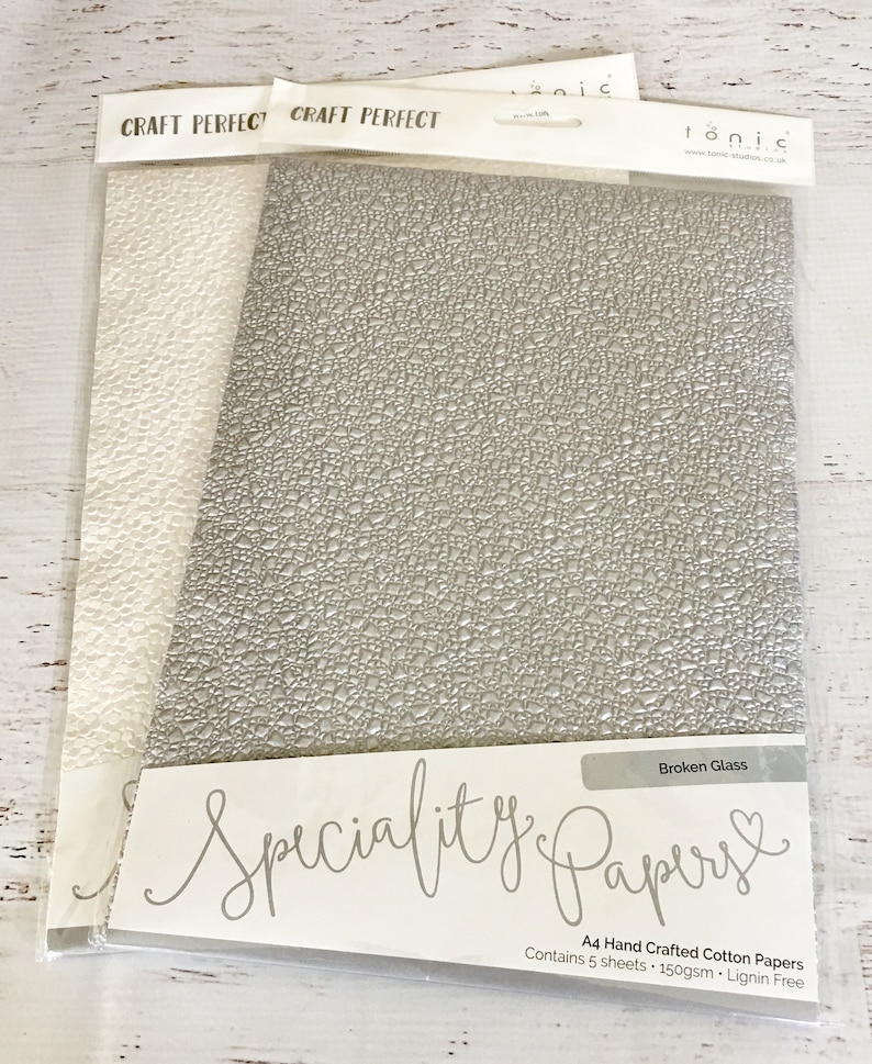 May include: A pack of 5 sheets of A4 size, 150gsm, lignin free, hand crafted cotton paper with a broken glass texture. The paper is a light gray color and is packaged in a clear plastic bag with the brand name "Tonic" and the words "Specialty Papers" printed on the front.