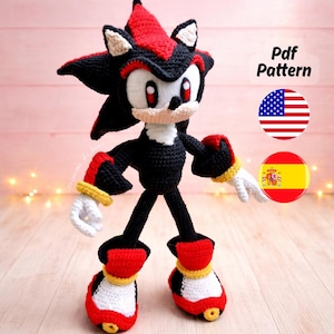 Może przedstawiać: Szydełkowa lalka Shadow the Hedgehog w kolorach czarnym, czerwonym, białym i żółtym. Lalka ma szczegółowy design z kolcami, białym korpusem i czerwonymi akcentami. Obraz zawiera tekst "Pdf Pattern" i flagi.
