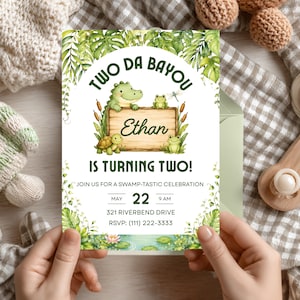 May include: A birthday invitation with a swamp theme. The invitation features a cartoon alligator, frogs, and a turtle. The text reads "Two Da Bayou" and "Ethan is turning two!" with event details.