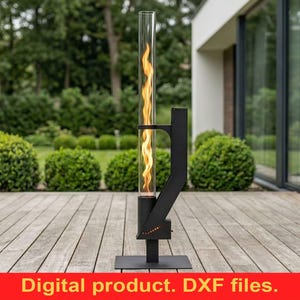 May include: A modern outdoor fireplace with a tall, clear glass tube containing a simulated flame. The fireplace is black and stands on a square base. The background includes a wooden deck, green lawn, and manicured bushes.