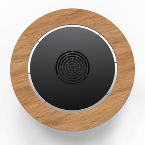 May include: Circular wooden coaster with a dark gray center and a silver trim. The center has a circular pattern. The coaster is made of wood and metal. The coaster is designed to hold a cup or glass.