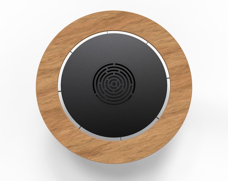 May include: Circular wooden coaster with a dark gray center and a silver trim. The center has a circular pattern. The coaster is made of wood and metal. The coaster is designed to hold a cup or glass.