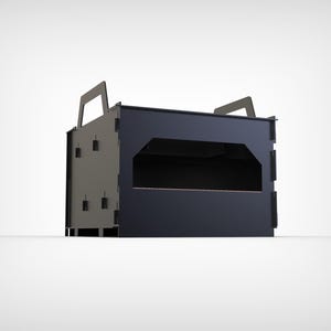 May include: A dark gray and black rectangular box with two handles on top. The box has a large rectangular opening in the front and several small rectangular cutouts on the sides. The box appears to be made of metal.