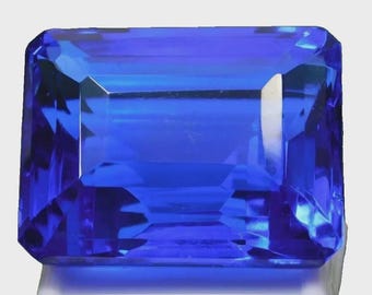 May include: A faceted, rectangular-cut gemstone with a deep blue hue. The gem's facets reflect light, creating a brilliant display. The gemstone is set against a white background, highlighting its color and clarity. This gem is suitable for jewelry.