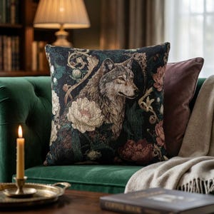 May include: A square throw pillow featuring a woven tapestry design of a wolf surrounded by large cream and dark red floral blooms and intricate gold scrollwork against a dark black background. The fabric has a textured, detailed appearance.