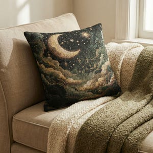 May include: A square throw pillow featuring a woven tapestry design of a night sky with a large golden crescent moon, scattered stars, and dark, textured clouds in shades of deep green, black, and gold, creating a celestial night scene.