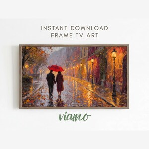 Pode incluir: Uma impressão de arte digital emoldurada retrata um casal caminhando sob um guarda-chuva vermelho em uma rua de paralelepípedos chuvosa. A obra de arte apresenta tons quentes, postes de luz e o texto "INSTANT DOWNLOAD FRAME TV ART". A palavra "viamo" também é visível.