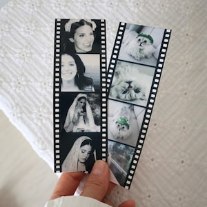 May include: Two vertical bookmarks designed to resemble strips of 35mm film. The left strip features four black and white portraits of a person. The right strip displays four images of a fluffy cat, including two wearing a small green hat.