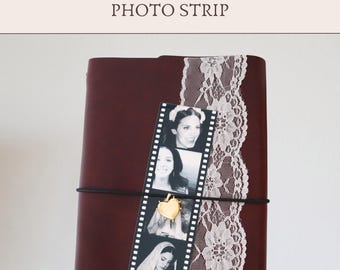 May include: A dark maroon leather-bound journal featuring a vertical strip of white floral lace and a black and white photo strip held in place by a thin black elastic band. A small gold heart-shaped charm is attached to the elastic over the photos.