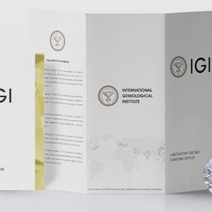 May include: A brilliant-cut diamond next to a white brochure with the IGI logo and text. The brochure is labeled "Laboratory Grown Diamond Report" and "International Gemological Institute". The diamond is round and faceted.