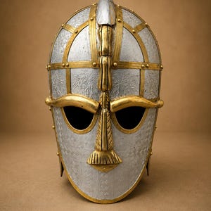 May include: A silver-colored metal helmet featuring a gold-colored metal framework and nose guard. The silver panels are decorated with intricate embossed patterns, while the gold accents include a central crest and brow piece over eye openings.