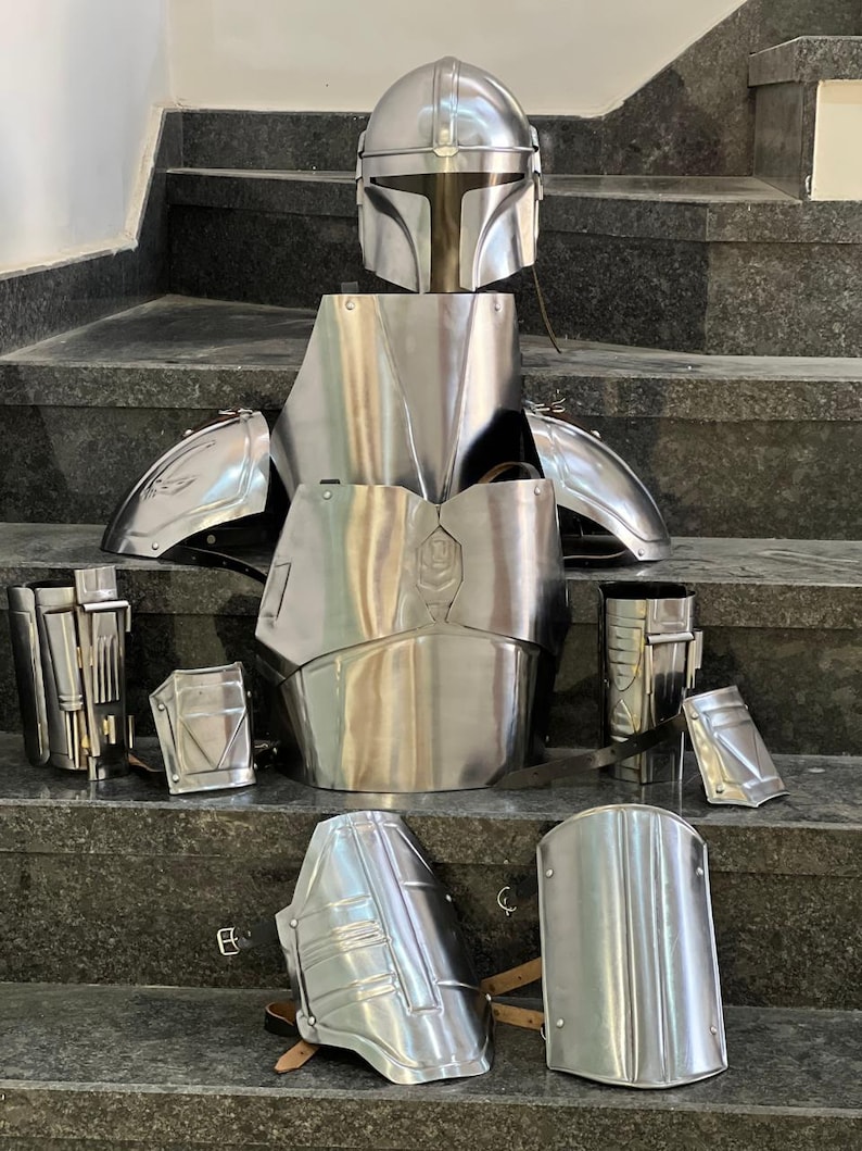 May include: A complete set of polished metal armor, including a helmet, chest plate, shoulder guards, arm guards, and leg guards. The armor is displayed on a set of stairs, showcasing its intricate design and reflective surface.