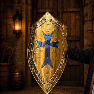 Op de afbeelding: Een goudkleurig schild met een blauw kruisontwerp. Het schild heeft een decoratieve rand en wordt gehouden tegen een vage achtergrond van een houten deur en stenen muur. Het schild is een middeleeuws thema.