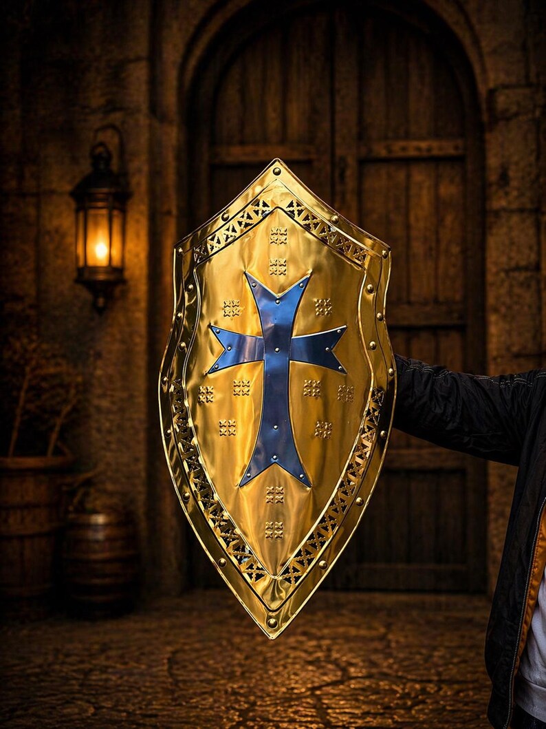 Op de afbeelding: Een goudkleurig schild met een blauw kruisontwerp. Het schild heeft een decoratieve rand en wordt gehouden tegen een vage achtergrond van een houten deur en stenen muur. Het schild is een middeleeuws thema.