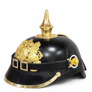 May include: Black leather helmet with gold-colored trim and a prominent gold spike on top. The helmet features a gold emblem on the front and a black leather strap with gold buckles. A historical military item.