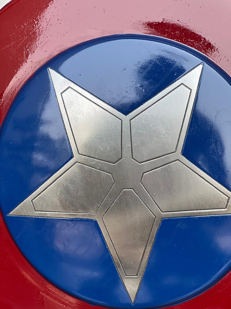 K&ouml;nnte beinhalten: Nahaufnahme eines rot, wei&szlig; und blau gehaltenen Schildes. Das Schild hat einen silbernen Stern in der Mitte, der sich vor einem blauen Kreis abhebt. Die &auml;u&szlig;eren R&auml;nder sind rot und gl&auml;nzend.