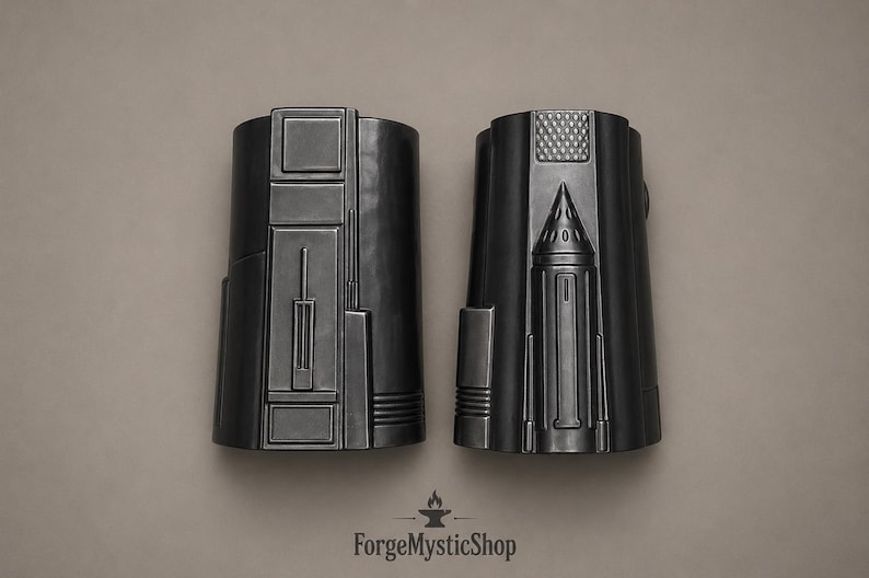 May include: Two matte black forearm guards featuring intricate geometric paneling and raised structural details. The left guard displays rectangular segments, while the right guard features a central conical protrusion and a textured grid pattern.