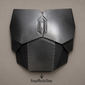 May include: A matte black chest plate armor piece featuring a geometric, multi-panel design with a central vertical rectangular emblem. The armor has a smooth, dark finish with sharp, angular edges and a symmetrical construction across the front.