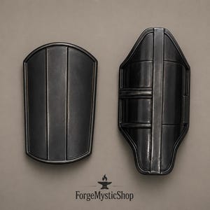 May include: Two black metal bracers with a smooth finish and raised vertical ridges. The left piece is a rounded rectangular shape, while the right piece features a contoured design with a central spine. The text ForgeMysticShop is at the bottom.