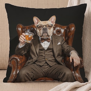 May include: A square throw pillow featuring a graphic print of a French Bulldog wearing a brown three-piece suit, a bow tie, and black-rimmed glasses. The dog is seated in a brown leather armchair, holding a glass of amber liquid with ice cubes.